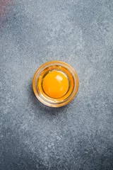  Close-up of the yolk of a chicken egg. On a gray stone background. Top view. © Yaruniv-Studio