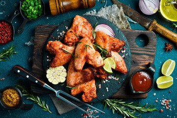 Grilled chicken wings with garlic and rosemary on a slate plate. On a dark background. - 788118808