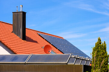 Photovoltaikanlage auf rotem Hausdach und Solarthermieanlage auf Garagendach - obrazy, fototapety, plakaty