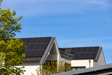 Solaranlagen auf Hausdächern vor blauem Himmel - obrazy, fototapety, plakaty