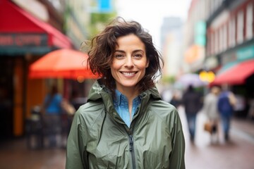 Portrait of a content woman in her 40s wearing a lightweight packable anorak over vibrant market street background