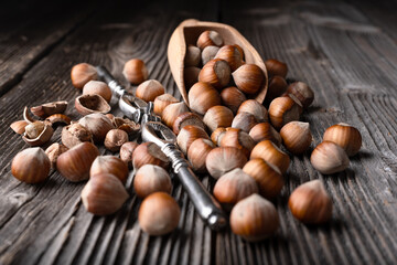 Whole and cracked hazelnuts with a classic silver nutcracker on wooden table close up. Food photography