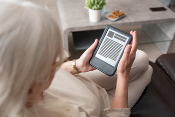 Woman sitting on the sofa, reading an e-book