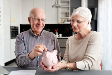 Senior couple puts a coin in a piggy bank