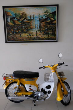 old Honda C70 motorbike. first launched in 1969. natural landscape paintings on the walls. vintage motorcycle. 
