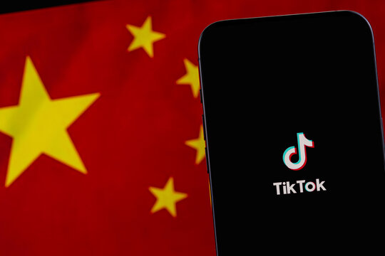 TikTok mobile icon app on screen smartphone iPhone, flag of China background. TikTok is app to create and share videos. Moscow, Russia - December 21, 2023