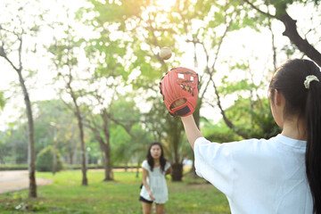 Active mother and daughter playing in baseball at public park. Family, sports and leisure activity concept