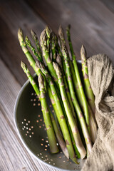 Fresh sprouts of picked asparagus in metal colander on wooden table. Top view. Food photography