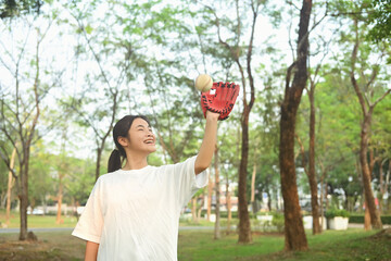 Cheerful asian girl in leather baseball glove catching ball. Sport, activity and people concept