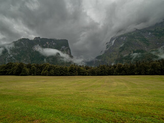 Green grass at the foreground and the huge mountain rocks of the Watzmann with dark rain clouds...