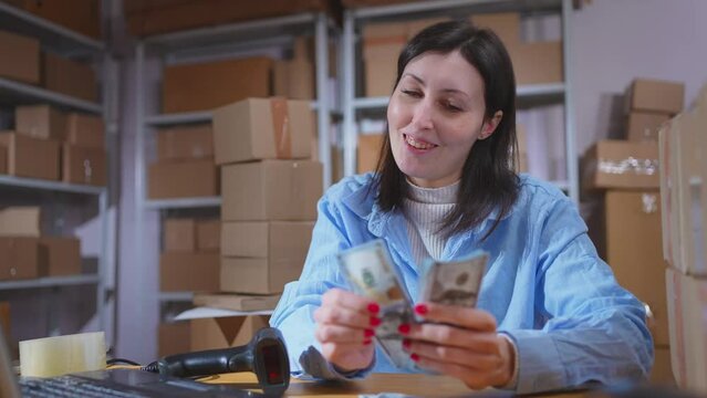 a satisfied businesswoman counts a stack of banknotes and fixes a profit close up