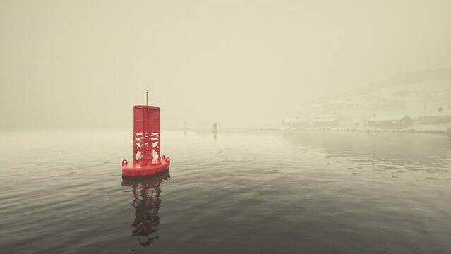 A red metal buoy floats on top of the cold Norwegian sea.