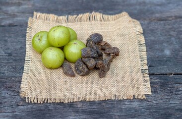 Amla Fruit or Indian Gooseberry Candy on Burlap Fabric Isolated on Wooden Background with Copy Space, Also Known as Emblica Myrobalan or Phyllanthus Emblica