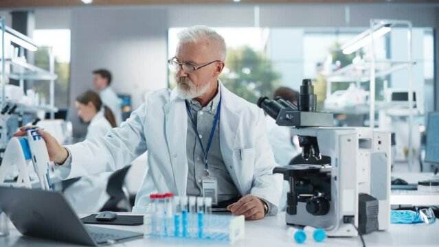 Medical Research and Development Laboratory: Senior Caucasian Male Scientist in Glasses Looking at a Sample in a Petri Dish Under a Microscope in an Advanced Biotechnology Lab