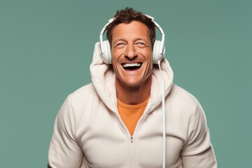 Portrait of a grinning man in his 40s wearing a zip-up fleece hoodie and headphones over pastel or soft colors background - obrazy, fototapety, plakaty