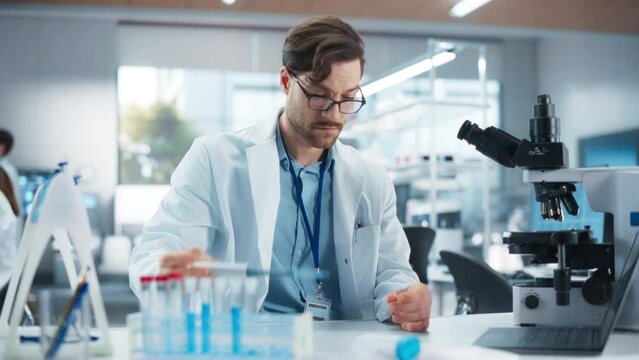 Portrait of a Handsome Scientist Using Micropipette to Analyze Genetic Samples Under Microscope. Advanced Scientific Medical Research Laboratory for Microbiology Products Development
