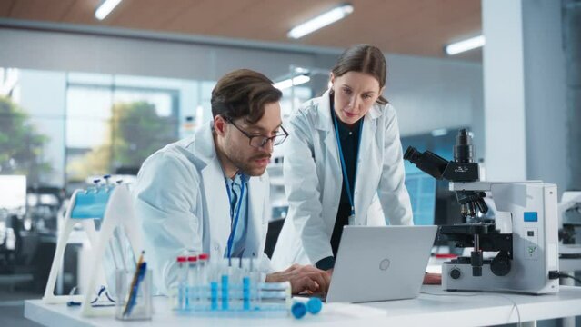 Scientists Working Together on a Research Project. Young Man and a Female in Modern Medical Laboratory Talking About Vaccine Development Methods, Gene Editing Studies, Biotechnology Breakthroughs
