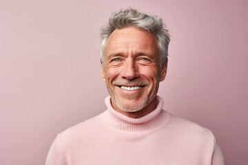 Obraz premium Portrait of a smiling man in his 60s wearing a classic turtleneck sweater on pastel or soft colors background