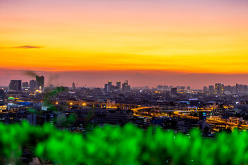 Fototapeta premium High angle background of the evening atmosphere of the condo rooftop overlooking the twilight sky and houses. Tall buildings and blurry lights in the business district