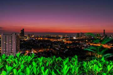 High angle background of the evening atmosphere of the condo rooftop overlooking the twilight sky and houses. Tall buildings and blurry lights in the business district