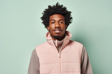 Portrait of a satisfied afro-american man in his 20s dressed in a water-resistant gilet on pastel or soft colors background