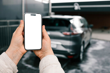 Hands with a blank phone screen on the background of a car wash