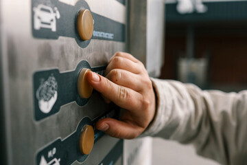 Close up of a hand pressing a button on a self-service coin machine at car wash