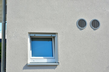 Moderne Fenster in einer verputzten und gestrichenen Fassade eines modernen Wohnhauses