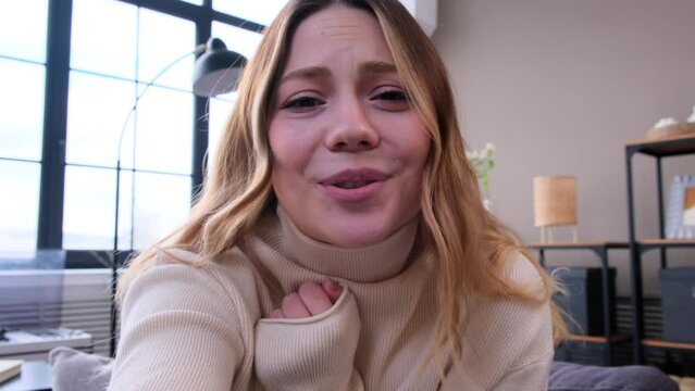 Friendly Caucasian woman sending air kiss on video call and saying goodbye at home. Female blogger recording video for online social media.