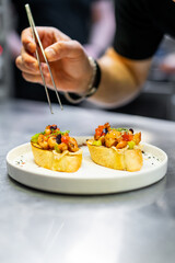 A meticulous chef garnishing gourmet appetizers with tweezers, showcasing the precision and artistry of high-end cuisine