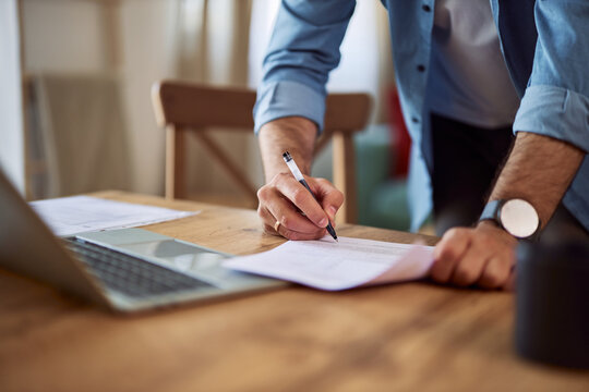 Close-up of a male hand signing a document for administrative work.