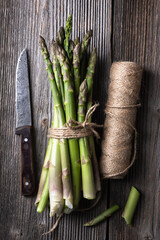 Bunch of fresh asparagus sprouts and skein of twine on old wooden table. Top view. Food photography