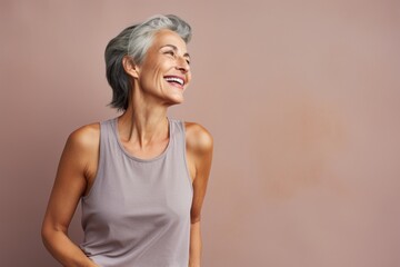 Portrait of a joyful woman in her 50s dressed in a breathable mesh vest in minimalist or empty room background