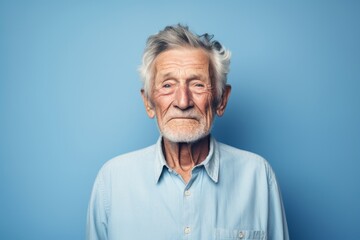 Portrait of a happy elderly 100 years old man sporting a versatile denim shirt on minimalist or empty room background