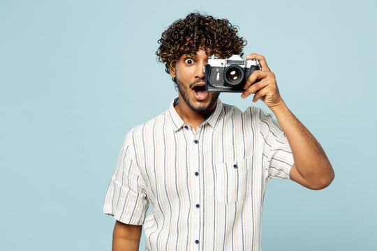 Traveler shocked Indian man wear white casual clothes use camera taking photo picture isolated on plain blue background. Tourist travel abroad in free spare time rest getaway. Air flight trip concept.