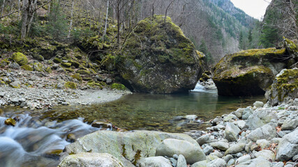 A waterfall in Latorita Gorges. The mountain river formes a narrow canyon as it flows through boulders and cliffs, near forests. The stream forms multiple ponds eroded in stone. Romania.