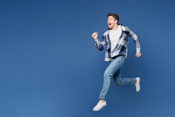 Fototapeta na wymiar Full body side profile view excited happy young man he wear shirt white t-shirt casual clothes jump high run fast hurrying up isolated on plain blue cyan background studio portrait. Lifestyle concept.