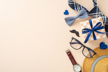 Festive composition for Fathers' Day with straw hat, elegant necktie, bow tie, gift box, glasses, mustache, wristwatch on pastel beige. Suitable for greetings or ads. Top view with space for message