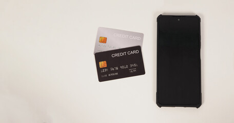 Two credit cards and mobile phone on white background.
