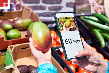Checking calories on a mango fruit in store with smartphone