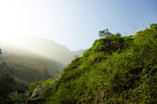 View of warm-toned green mountain valley during sunrise, mountain background with sand storm, Santo Antao island, Cape Verde.