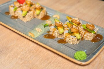 Close-up of a beautiful sushi plate made of rice, sesame, salmon, cucumber, avocado, a flower with wasabi and ginger, selective focus. Concept of food.