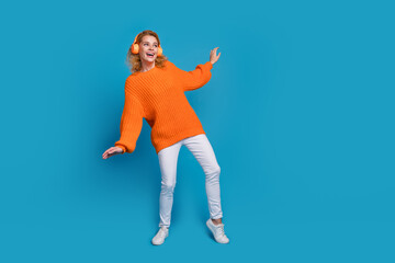 Fototapeta na wymiar Photo of positive good mood woman wear trendy orange clothes listen music look empty space isolated on blue color background