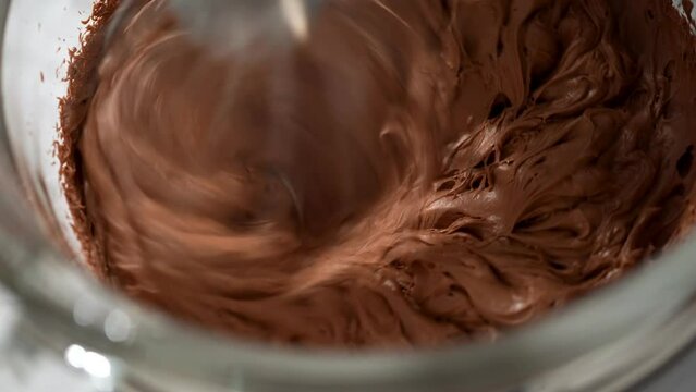 Whipping chocolate ganache with an electric kitchen mixer.