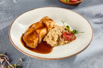 Grilled Chicken Breast with Mushroom Risotto Drizzled with Gravy on a Speckled Plate