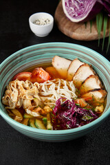 Chinese soup with noodles, chicken meat and vegetables in ceramic bowl on dark background. Asian cold soup in korean style and pick up noodles. Chinese cuisine in modern style.. - 788218447
