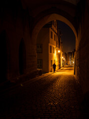 Person walking the streets of Rothenburg ob der Tauber at night, framed by an archway