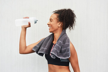 Black woman, athlete and drinking water in studio, training and hydration after workout on white...