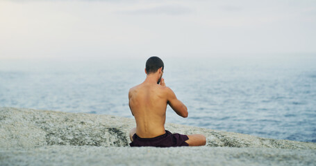 Calm, yoga or man at sea in meditation for peace, wellness or mindfulness in outdoor nature to relax. Chakra, holistic or back view of yogi on rock at beach for awareness or balance in pilates