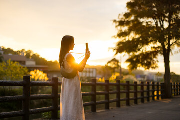 Woman take photo on cellphone under sun flare in the countryside